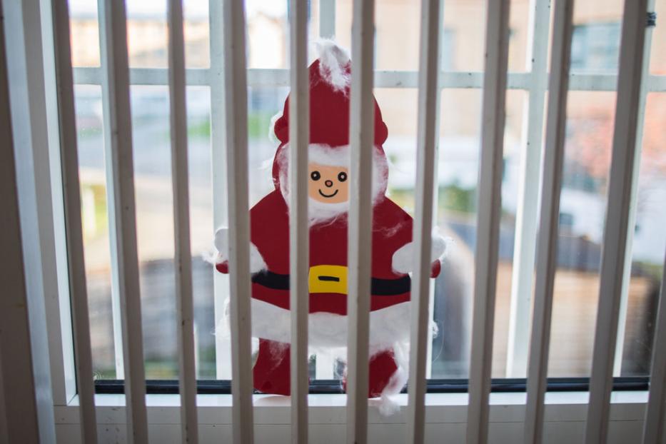 Ein Weihnachtsmann aus Papier hinter Gefängnis-Gittern