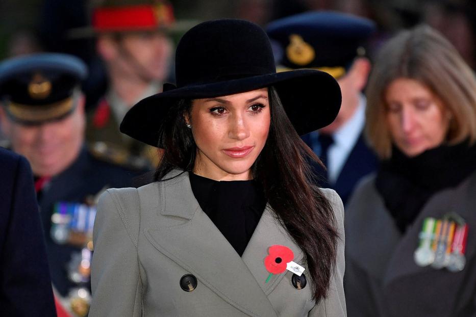 Meghan, Herzogin von Sussex, trägt einen Hut und einen Mantel mit einer Mohnblume.