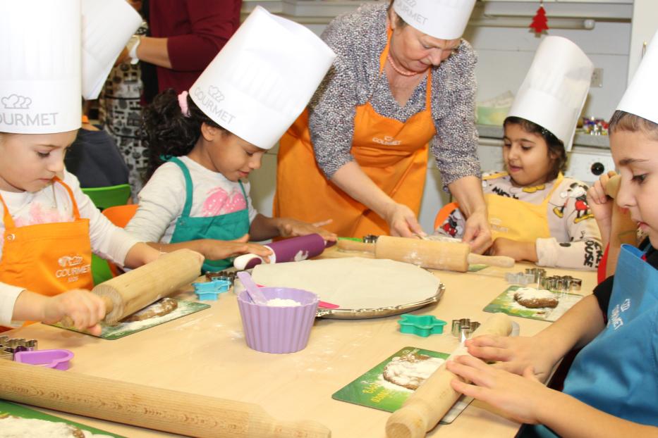 Kinder backen mit einer älteren Frau in einer Küche Kekse.