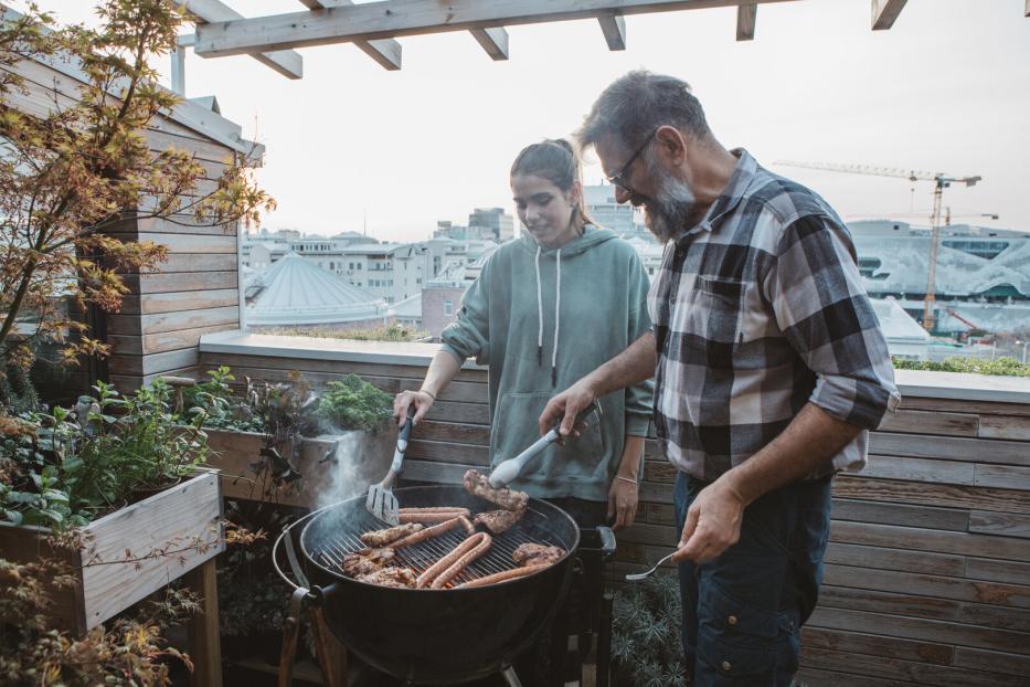 Älterer Mann und jüngere Frau grillen