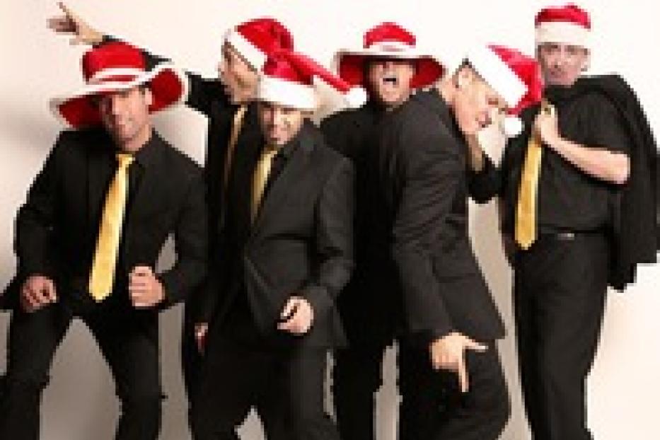 Eine Gruppe von sechs Männern in Anzügen und Weihnachtsmützen posiert.