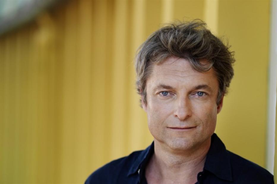 Porträt des österreichischen Schauspielers Alfred Dorfer vor einem gelben Hintergrund.
