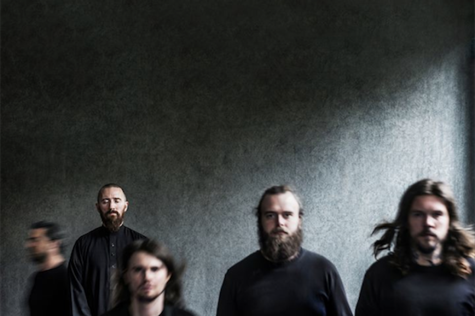 Die Band Amenra steht vor einer grauen Wand.