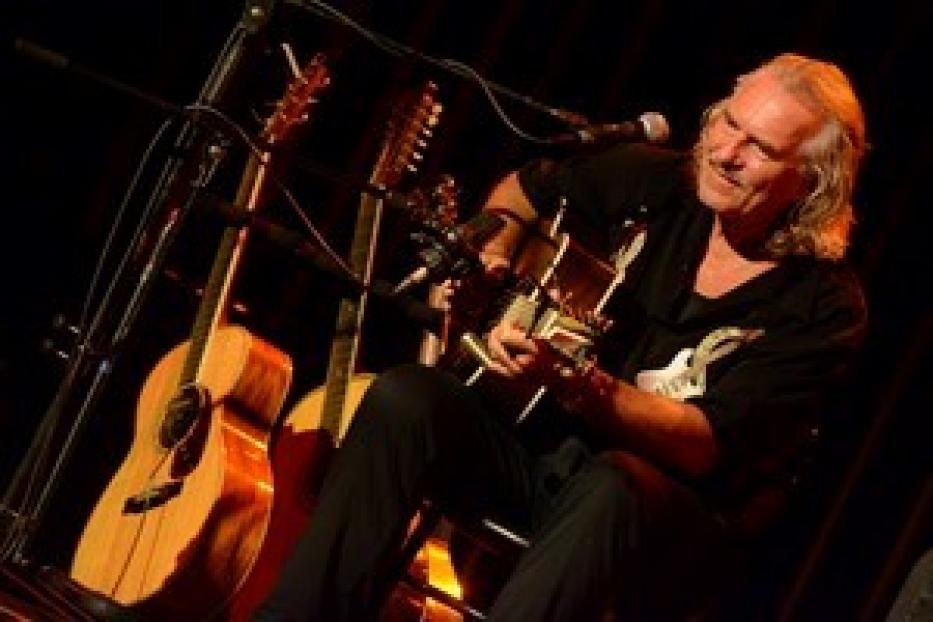 Thees Uhlmann spielt Gitarre auf einer Bühne.
