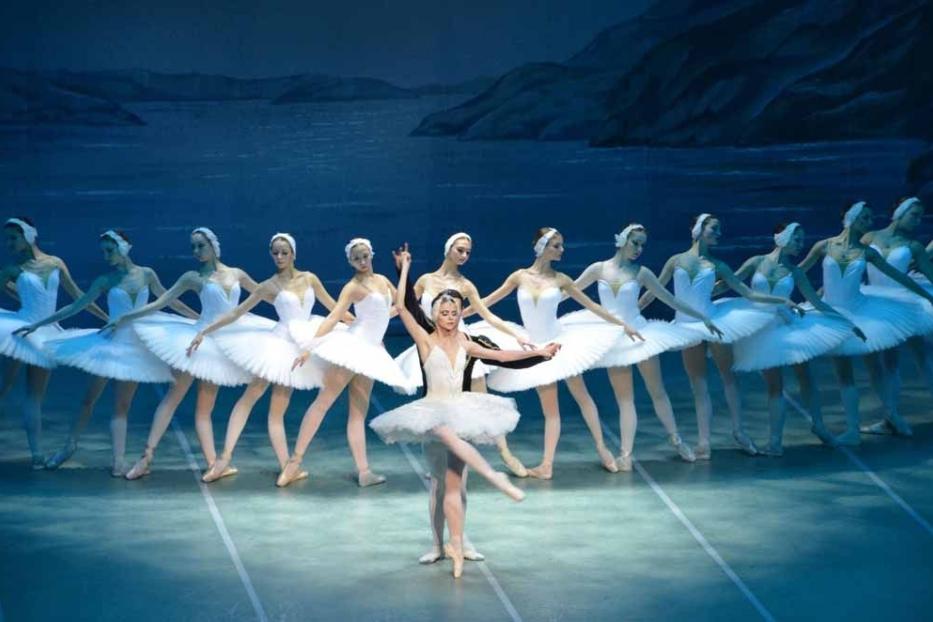 Eine Ballerina tanzt mit einem männlichen Partner vor einer Gruppe von Ballerinen im Schwanensee-Ballett.