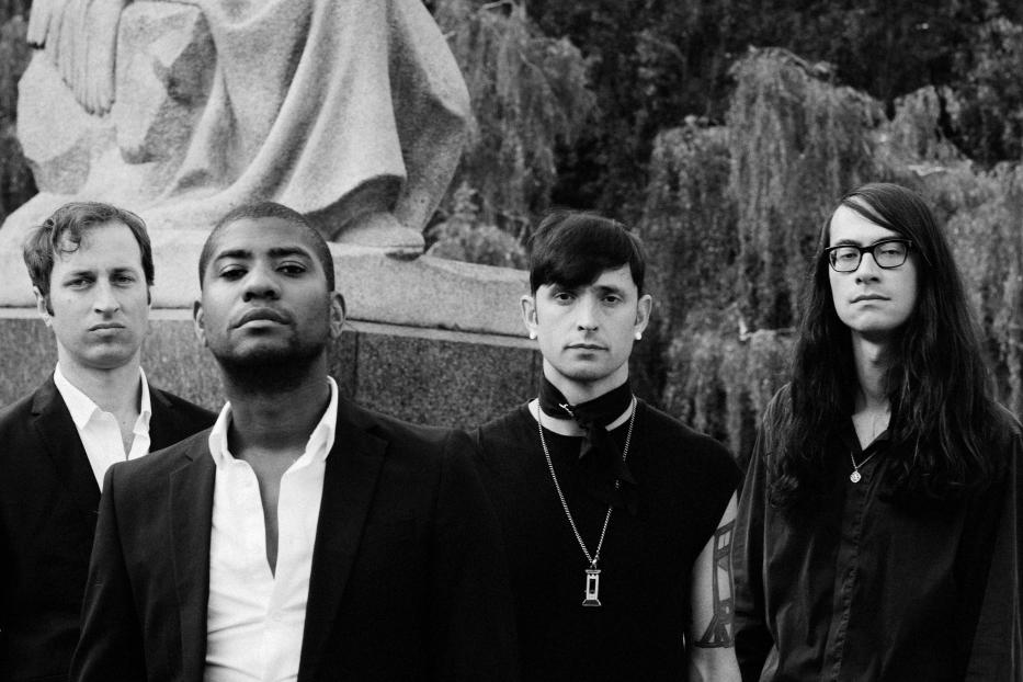 Die Band Algiers posiert vor einer Statue in Schwarzweiß.