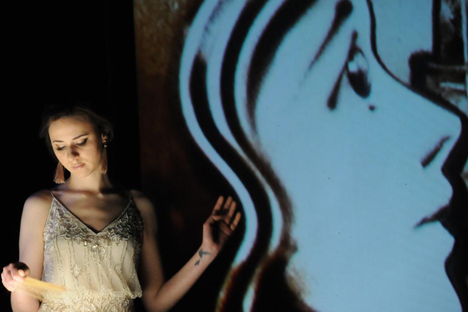Irina Titova bei einer Sandkunst-Performance, bei der ein Porträt projiziert wird.