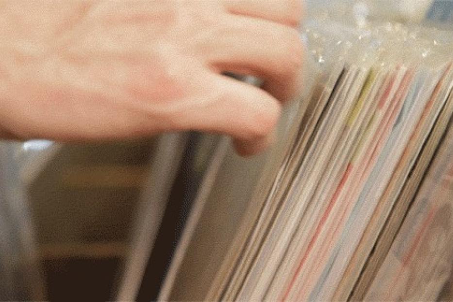 Eine Hand durchsucht eine Reihe von Schallplatten in einem Geschäft.