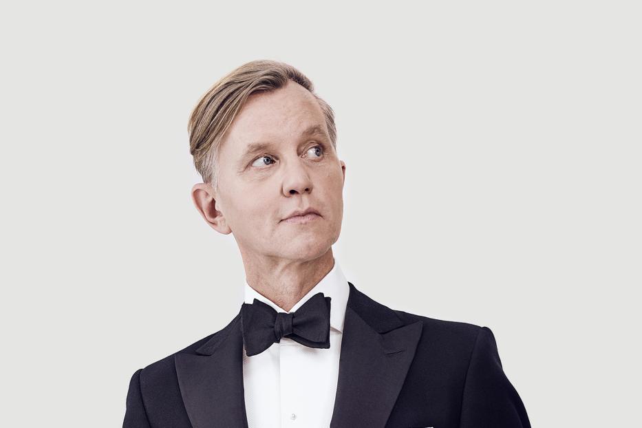 Ein Porträt von Max Raabe im Smoking, der nach oben links blickt.