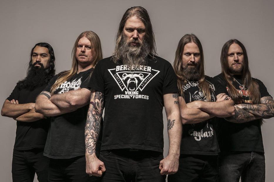 Die schwedische Metal-Band Amon Amarth posiert vor einem grauen Hintergrund.
