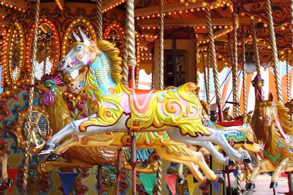 Ein buntes Karussellpferd mit goldenen Verzierungen und Lichtern.