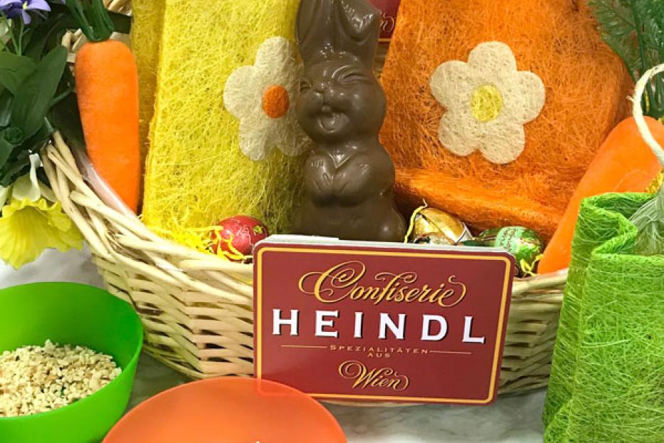 Ein Osterkorb mit einem Schokoladenhasen und Süßigkeiten der Confiserie Heindl.
