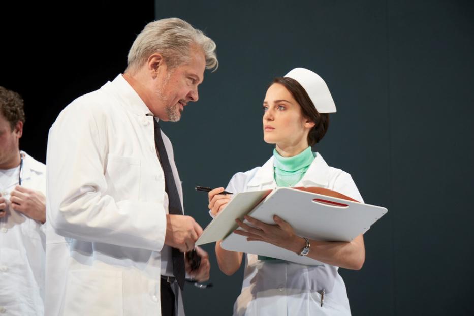 Ein Arzt spricht mit einer Krankenschwester, die ein Klemmbrett hält.