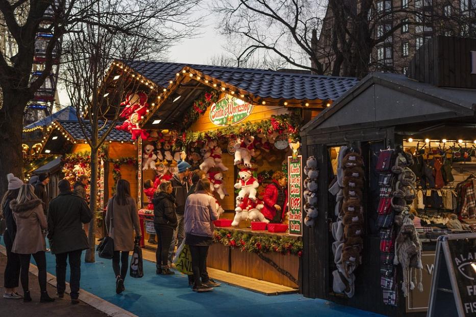 Besucher auf einem Weihnachtsmarkt vor einem Stand mit dem Schild „Santa's Workshop“.