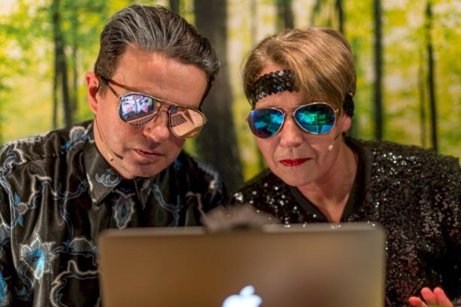 Johannes Gellner und eine Frau mit Sonnenbrillen schauen auf einen Laptop.