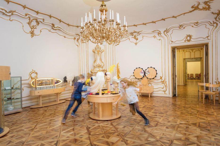 Zwei Kinder rennen in einem Raum des Kindermuseums Schloss Schönbrunn.