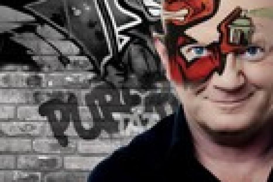 Ein Mann mit einem aufgemalten Teufelsgesicht vor einer Graffitiwand.