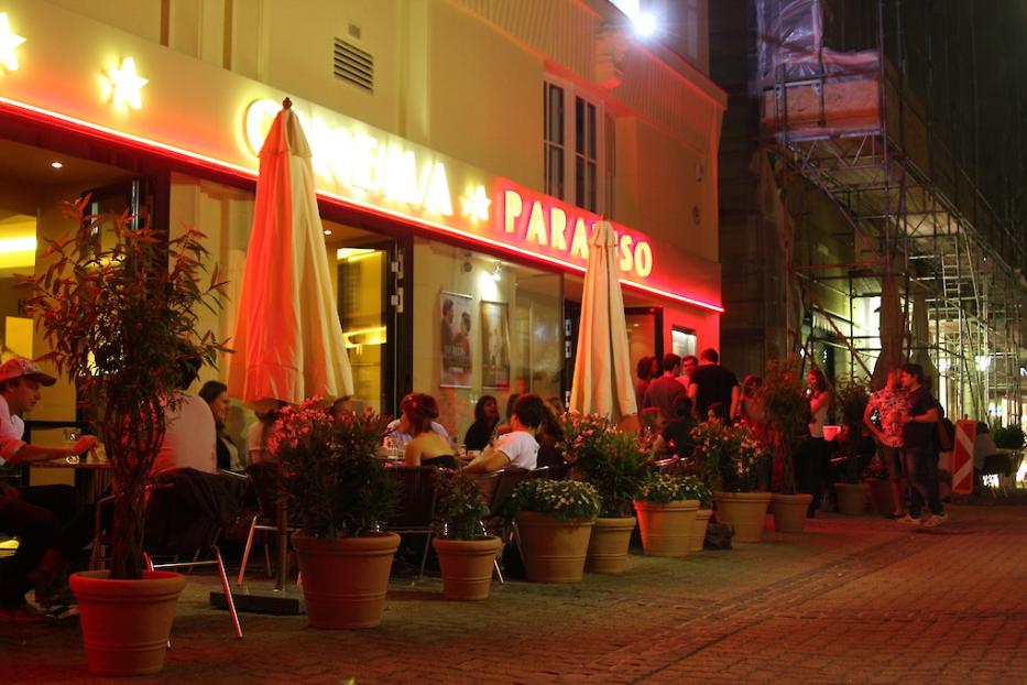 Menschen sitzen vor dem „Cinema Paradiso“ in Baden-Baden.