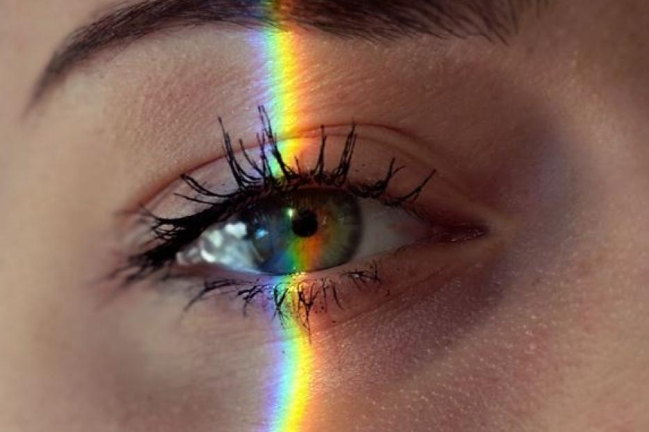 Ein Regenbogenstreifen fällt über das Auge einer Frau.