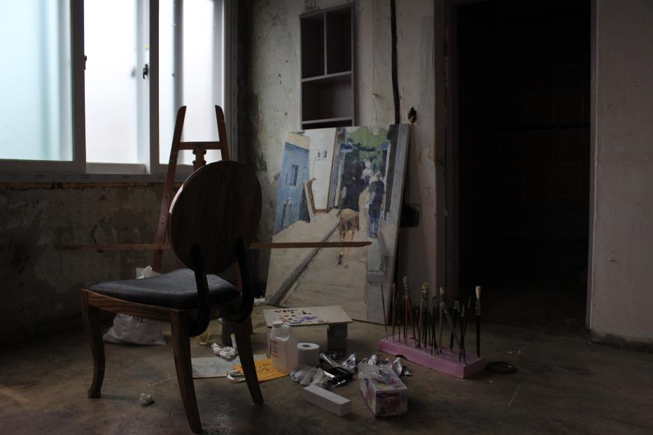 Ein Atelier mit einem Stuhl, einer Staffelei und einem unvollendeten Gemälde.