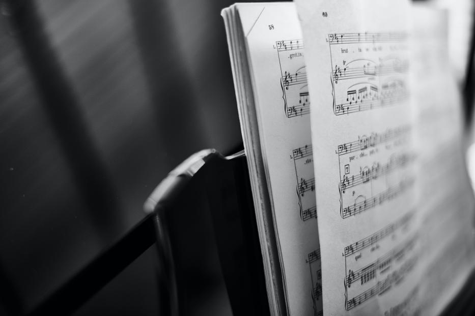 Ein aufgeschlagenes Notenbuch auf einem Klavier in Schwarzweiß.