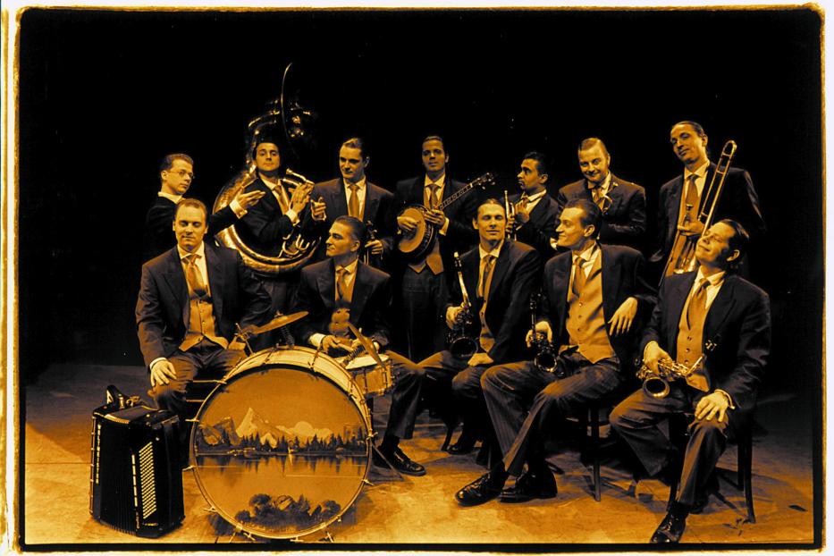 Eine Jazzband mit Blasinstrumenten, Banjo, Akkordeon und Schlagzeug posiert für ein Foto.