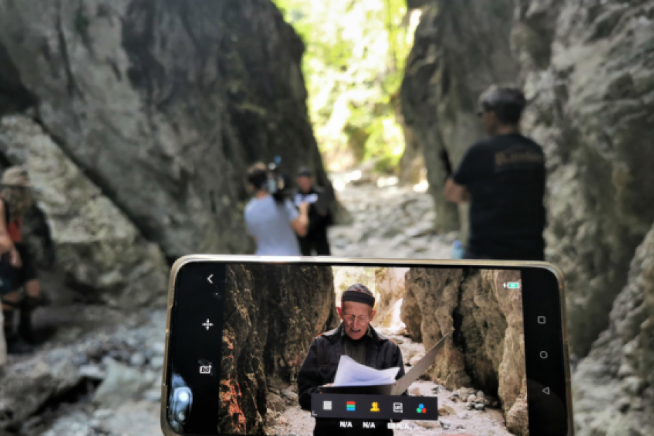Ein Mann liest in einer Schlucht einen Text vor, während er von einem Filmteam gefilmt wird.