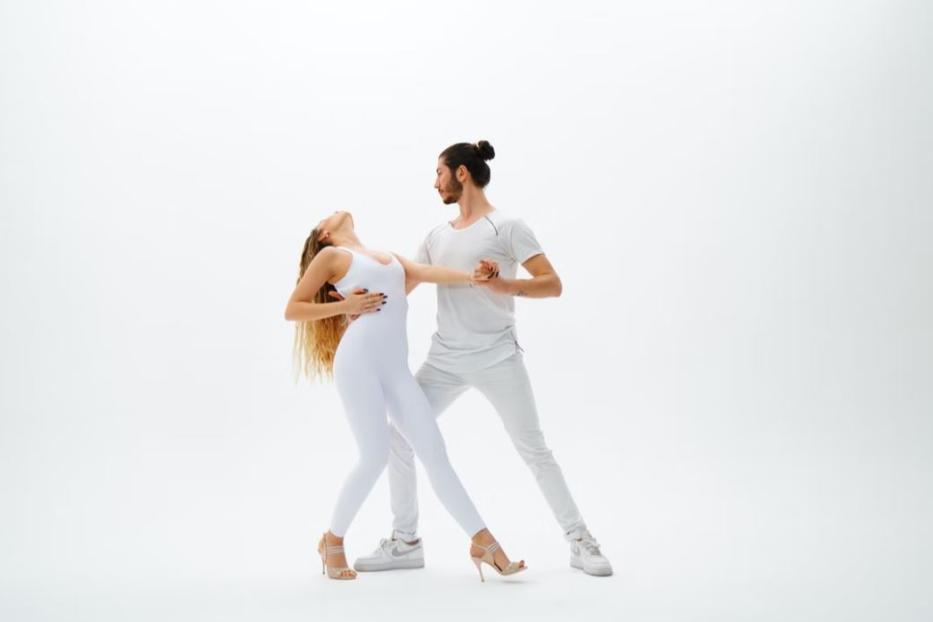 Ein Mann und eine Frau tanzen zusammen in einem hellen Studio.