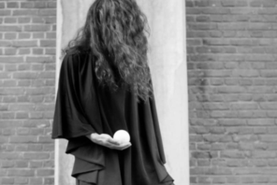 Eine Person in einem schwarzen Gewand hält eine weiße Kugel in der Hand.