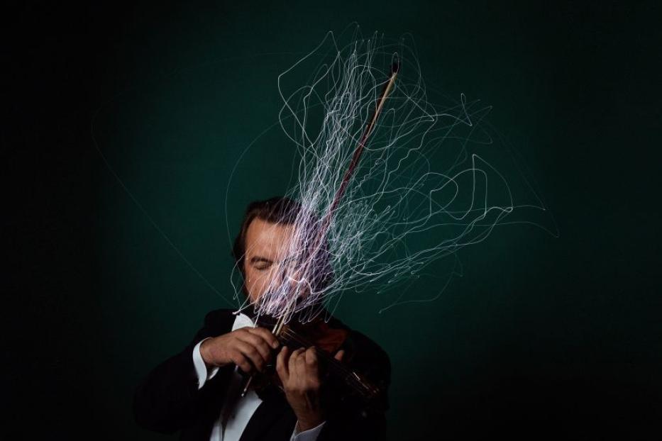 Ein Mann im Anzug spielt mit Lichteffekten Violine.
