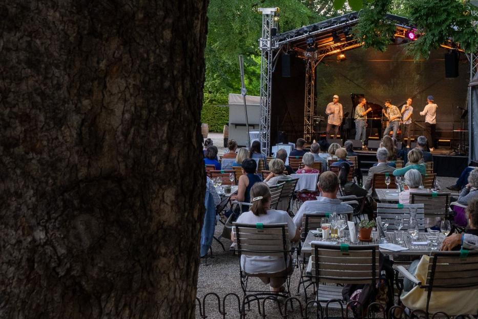 Eine Band spielt vor Publikum im Freien auf einer Bühne.