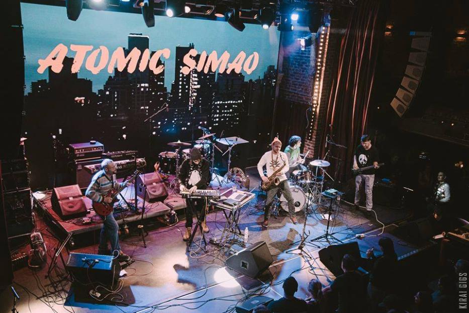 Die Band Atomic Simao spielt auf einer Bühne vor einem Publikum.