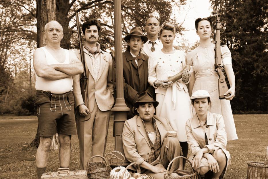 Eine Gruppe von Menschen posiert in historischer Kleidung mit Gewehren und Picknickkörben für ein Foto.