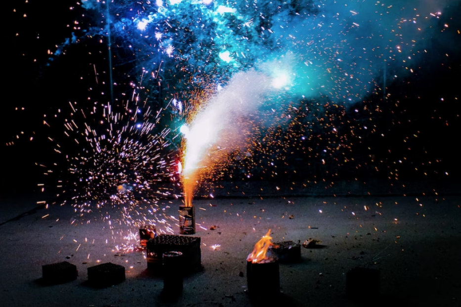 Feuerwerkskörper explodieren in einer dunklen Nacht mit blauem und goldenem Licht.