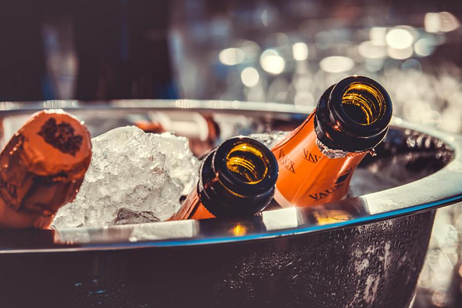 Mehrere Flaschen Sekt der Marke Vaux liegen in einem Eisbehälter.