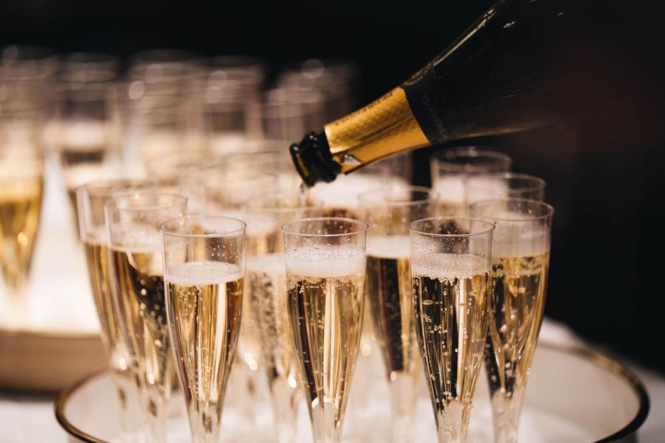 Champagner wird in viele Gläser eingeschenkt.