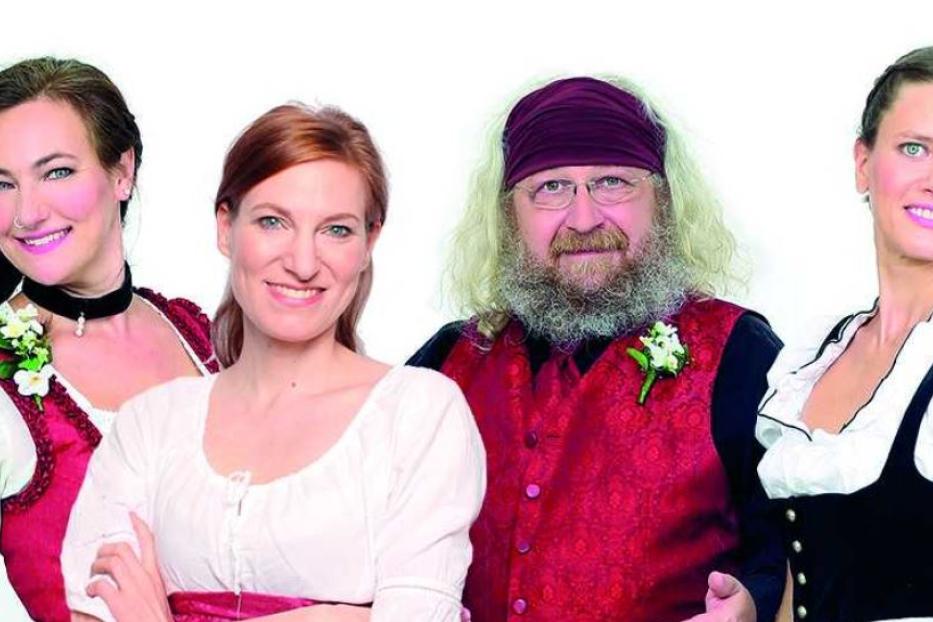 Eine Gruppe von vier Personen in Tracht vor einem weißen Hintergrund.