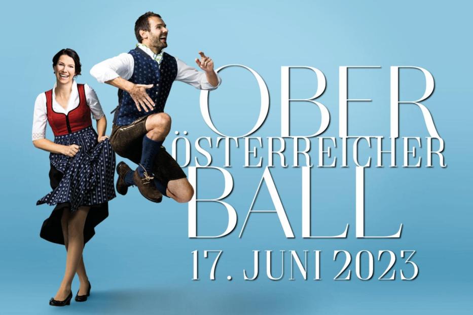 Ein Mann in Tracht springt vor dem Schriftzug „Oberösterreicher Ball 17. Juni 2023“, neben ihm eine Frau im Dirndl.