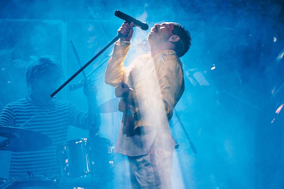 Ein Sänger performt mit einem Schlagzeuger im blauen Bühnenlicht.