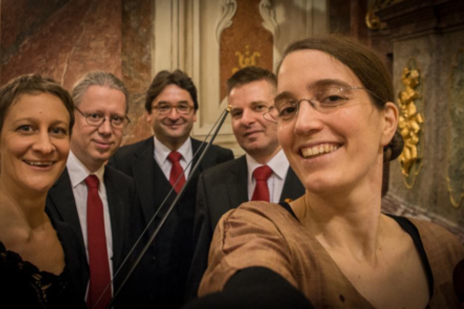 Ein Streichquartett posiert für ein Selfie in einem Konzertsaal.
