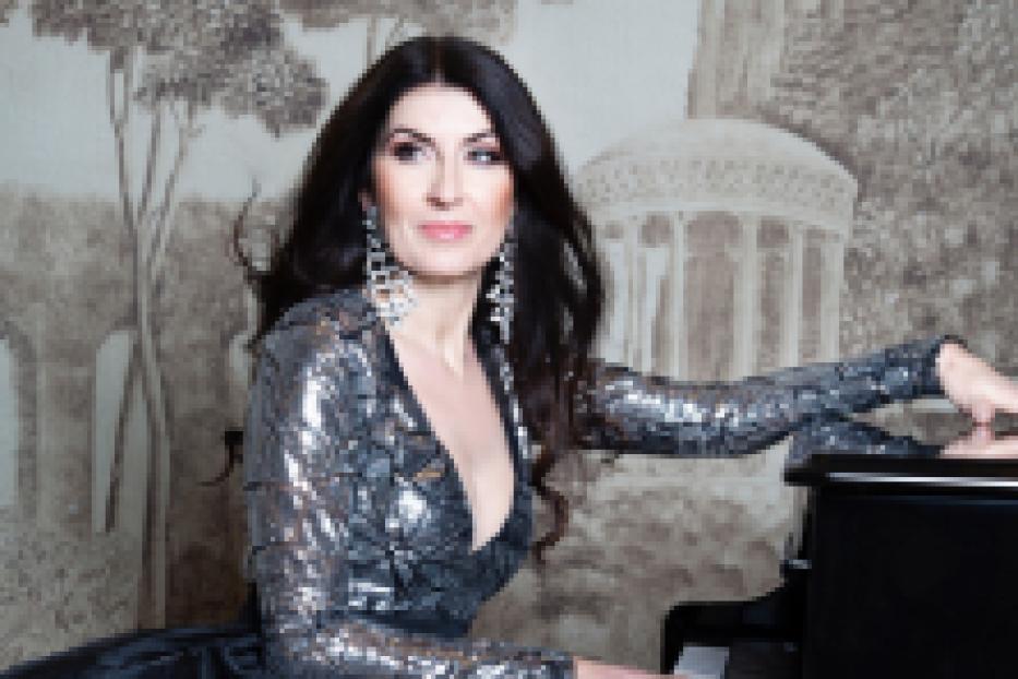 Eine Frau in einem glitzernden Kleid sitzt an einem Klavier.
