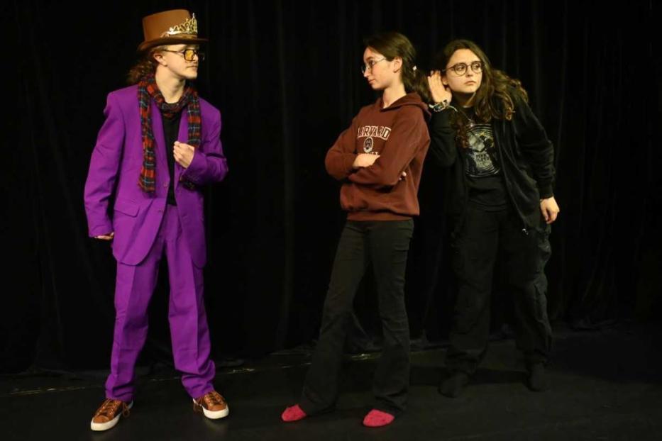 Ein als Willy Wonka verkleideter Teenager steht mit zwei weiteren Teenagern auf einer Bühne.