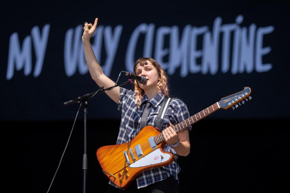 Eine Musikerin von My Ugly Clementine spielt Gitarre und singt auf einer Bühne.