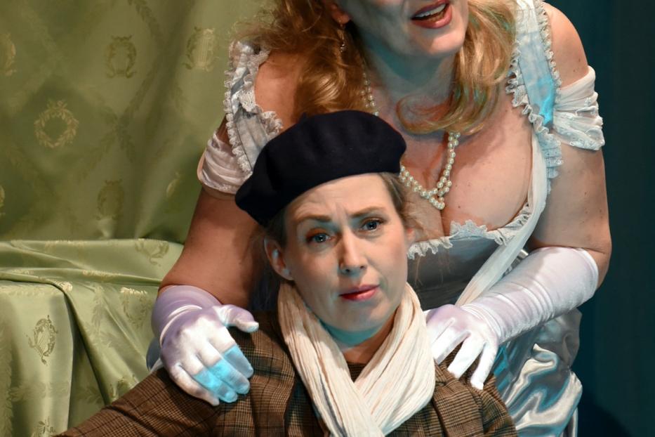 Zwei Frauen in Kostümen auf einer Theaterbühne.