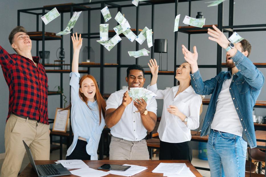 Happy business team of young multi-ethnic office employees celebrating victory and big profit.