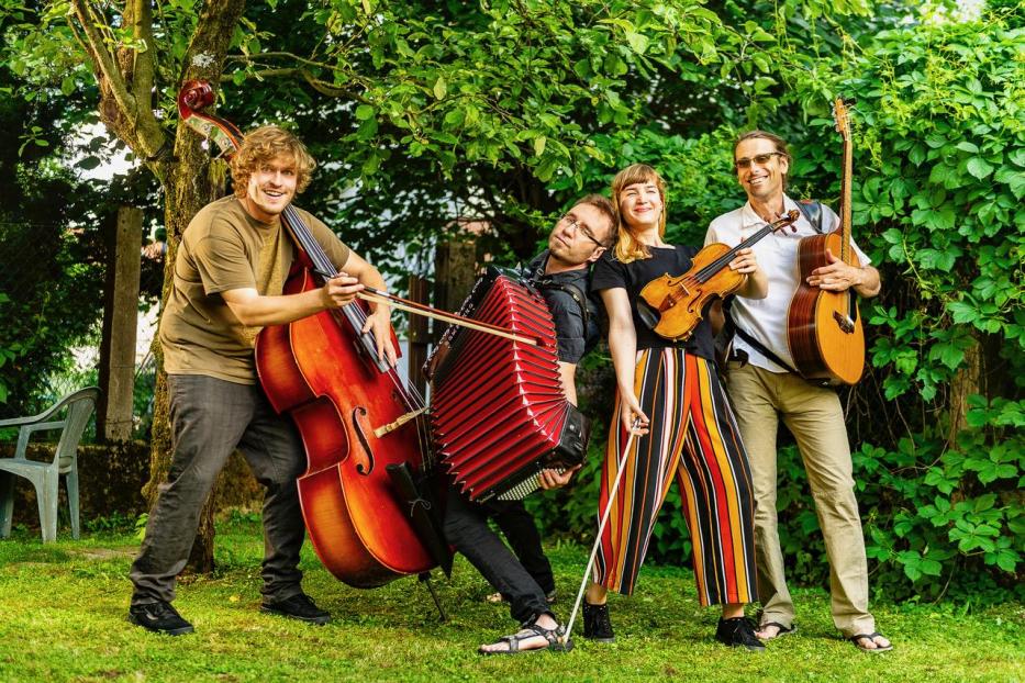 Die Brencl Banda posiert mit Kontrabass, Akkordeon, Geige und Gitarre im Grünen.
