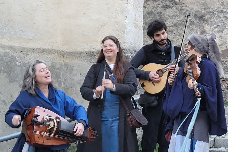 Eine Gruppe von vier Musikern spielt auf historischen Instrumenten im Freien.