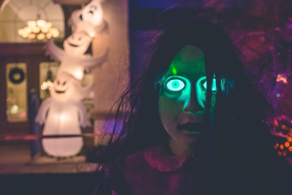Eine unheimliche Halloween-Dekoration mit leuchtenden Augen und Geistern im Hintergrund.