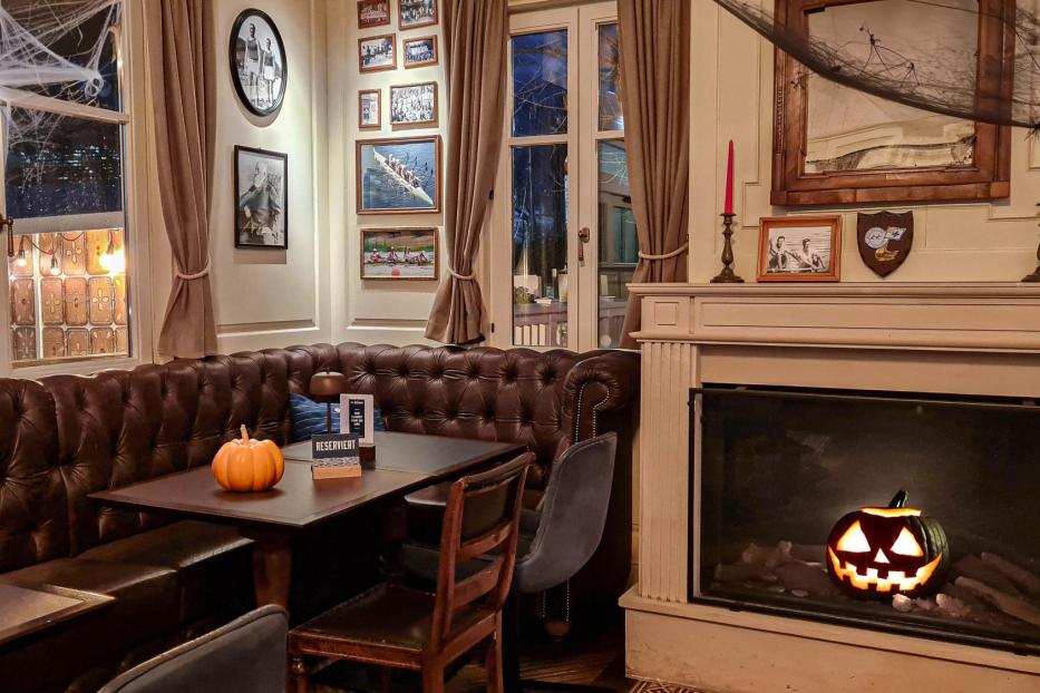Ein Restaurant mit Halloween-Dekoration, darunter Kürbisse und Spinnweben.