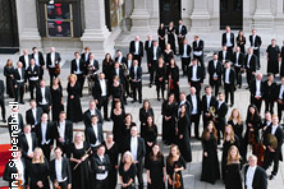 Ein großes Orchester steht vor einem Gebäude.
